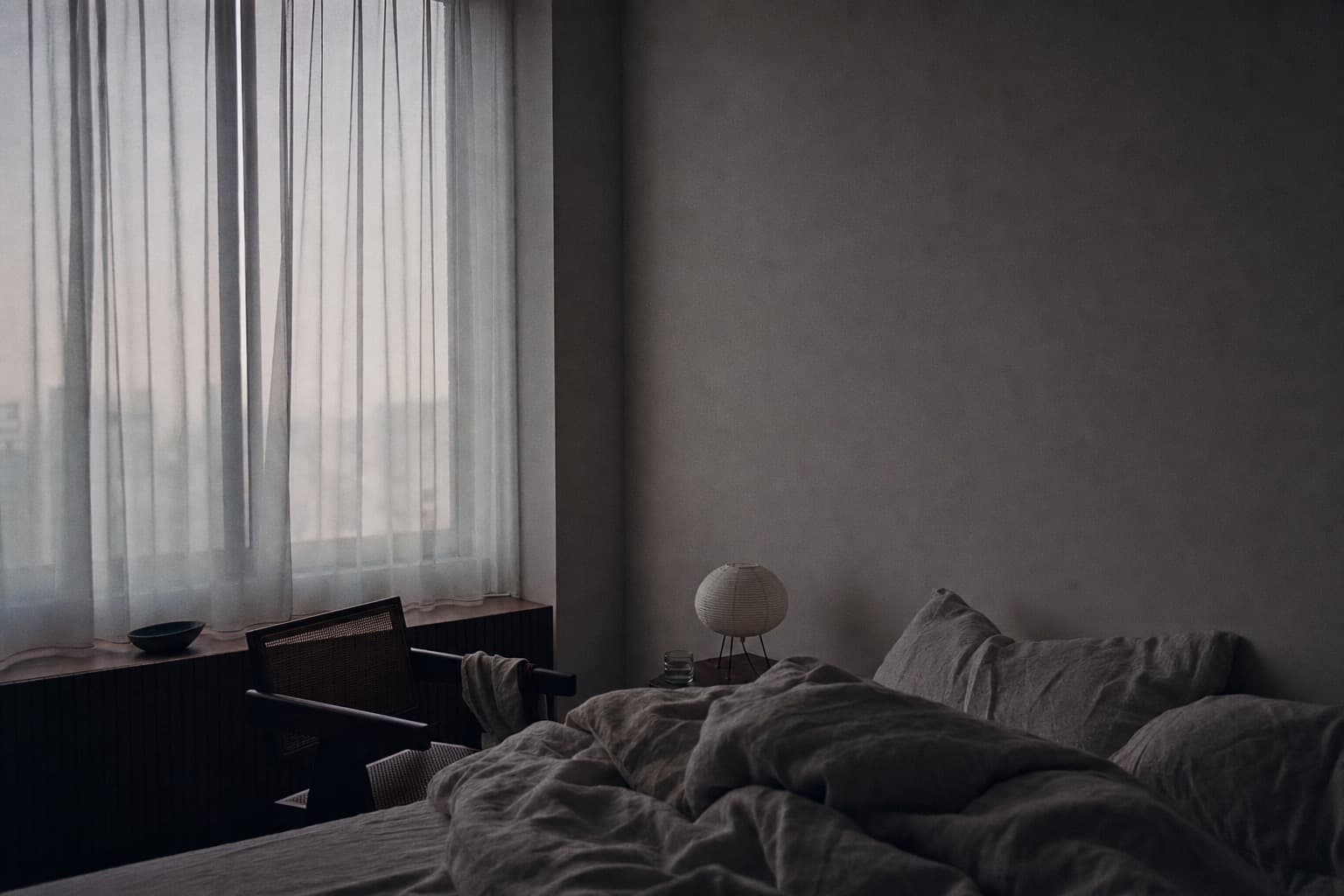 A dark, quiet bedroom with a neatly made bed